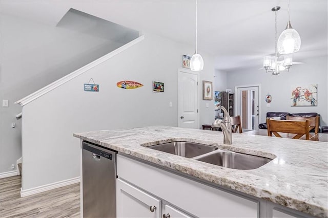 kitchen with dishwasher, light stone counters, a sink, and decorative light fixtures