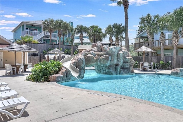 pool featuring a patio area, fence, and a water slide