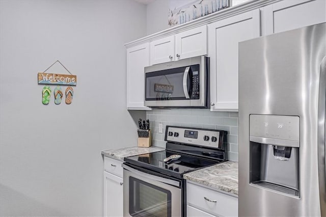 kitchen featuring white cabinets, light stone countertops, appliances with stainless steel finishes, and decorative backsplash