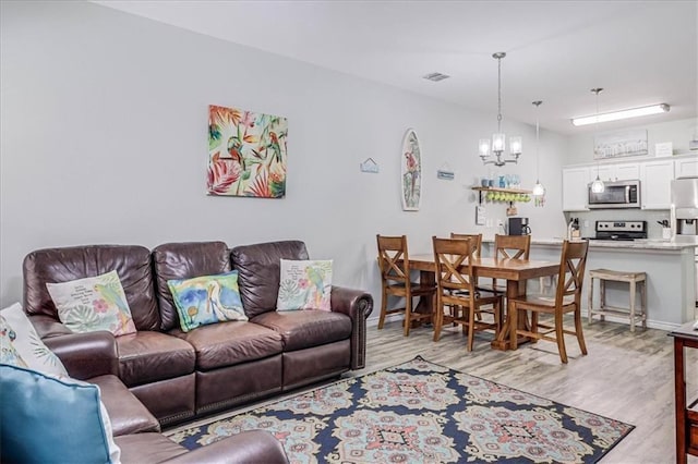 living room featuring light wood finished floors, baseboards, visible vents, and a chandelier