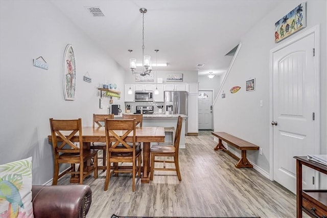 dining space with visible vents, a notable chandelier, light wood-style flooring, and baseboards