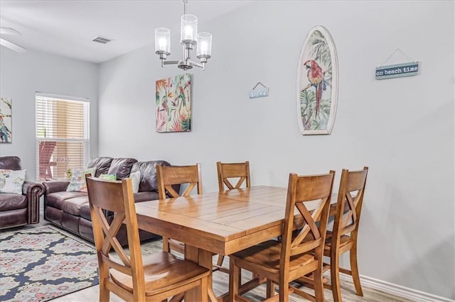 dining space with baseboards, light wood-type flooring, visible vents, and a notable chandelier