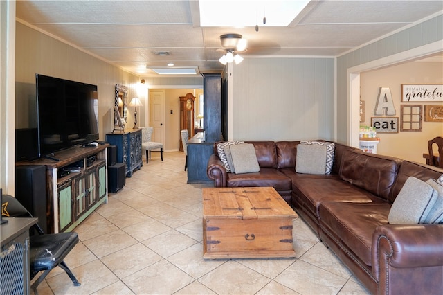 tiled living room with wood walls, ceiling fan, and ornamental molding