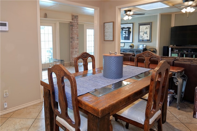 dining space with ceiling fan, light tile patterned floors, and a skylight