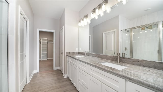 3634 Rebecca Dr, Corpus Christi, TX 78410 - full bathroom featuring double vanity, a walk in closet, a shower stall, wood finished floors, and baseboards