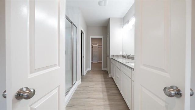3634 Rebecca Dr, Corpus Christi, TX 78410 - bathroom with a stall shower, wood finished floors, double vanity, a walk in closet, and baseboards