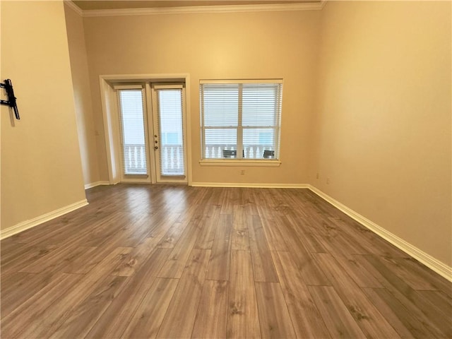 empty room featuring wood-type flooring, french doors, and crown molding