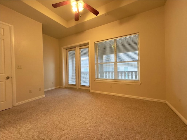 carpeted empty room with a tray ceiling and ceiling fan