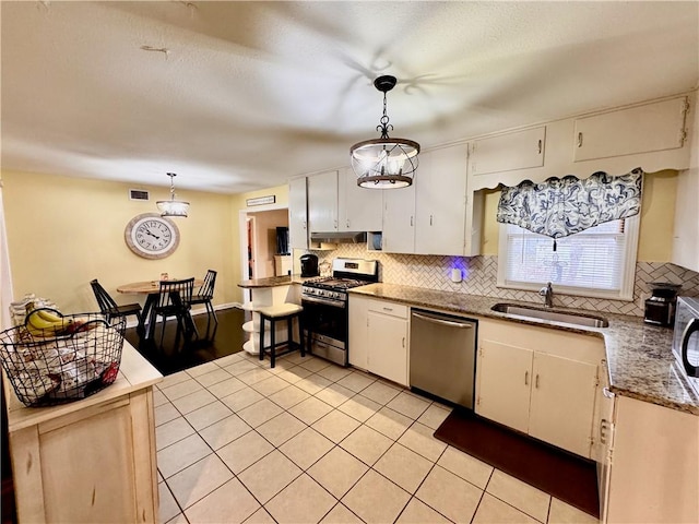 kitchen featuring stainless steel appliances, a sink, white cabinetry, hanging light fixtures, and tasteful backsplash