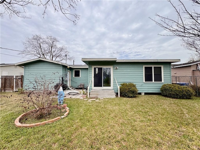 back of property featuring entry steps, a lawn, and fence