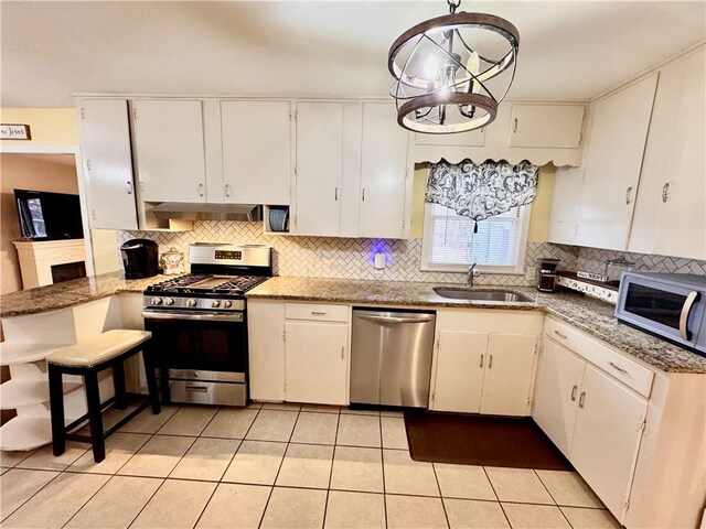 kitchen with appliances with stainless steel finishes, white cabinets, a sink, and backsplash