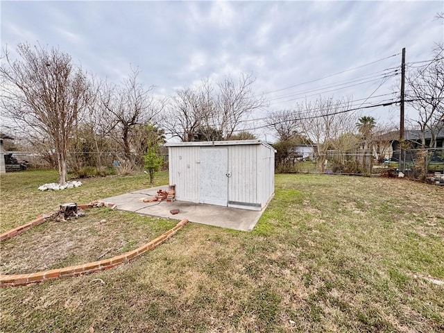 view of yard featuring fence, a storage unit, and an outbuilding