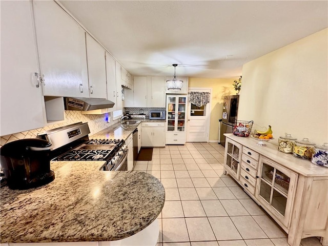 kitchen featuring stainless steel appliances, backsplash, light tile patterned flooring, white cabinets, and under cabinet range hood