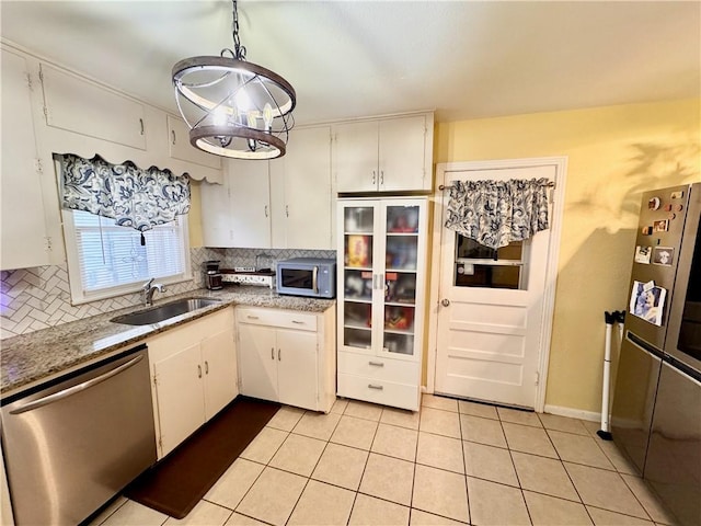 kitchen with light tile patterned floors, tasteful backsplash, appliances with stainless steel finishes, white cabinetry, and a sink