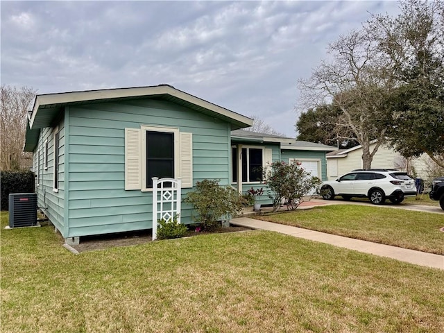 single story home with central AC unit, a front lawn, and an attached garage