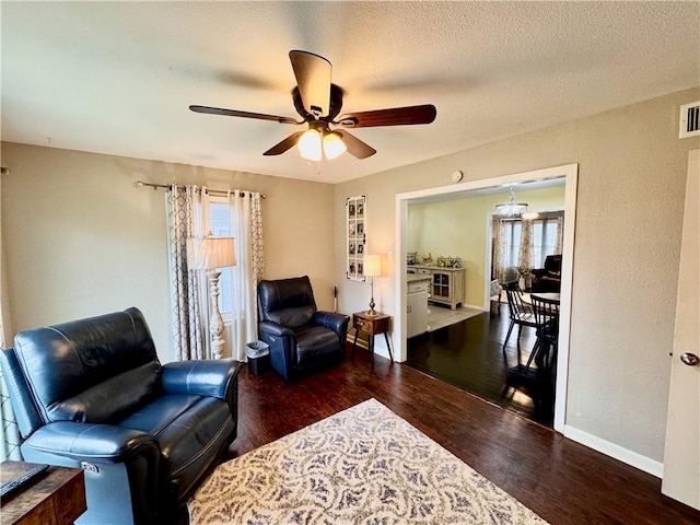 living area featuring baseboards, visible vents, ceiling fan, wood finished floors, and a textured ceiling