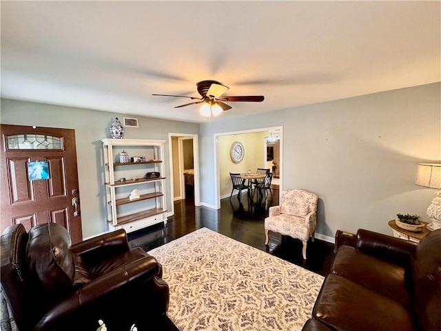 living room featuring a ceiling fan, dark wood finished floors, visible vents, and baseboards