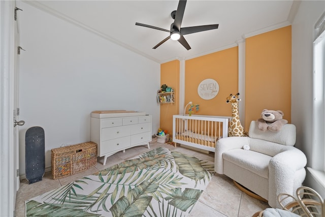 bedroom with a crib, ceiling fan, crown molding, and light tile patterned floors