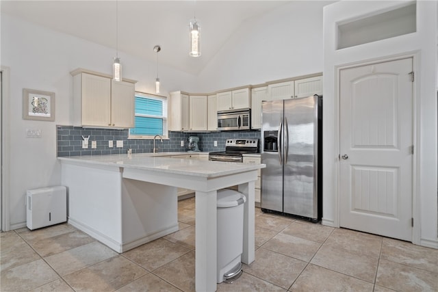 kitchen with stainless steel appliances, light tile patterned flooring, sink, kitchen peninsula, and decorative light fixtures