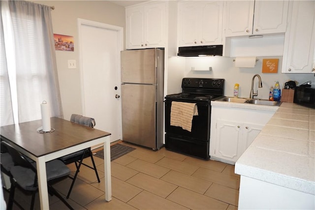 kitchen with freestanding refrigerator, black range with electric cooktop, under cabinet range hood, and white cabinetry