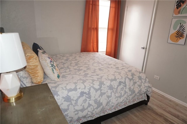 bedroom with baseboards and wood finished floors