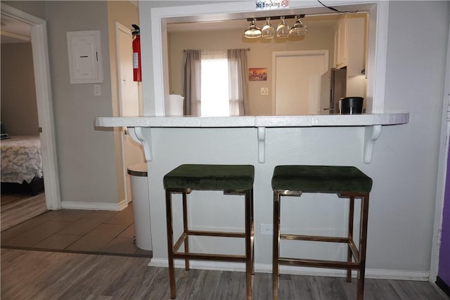 bar featuring electric panel, baseboards, dark wood-type flooring, and freestanding refrigerator