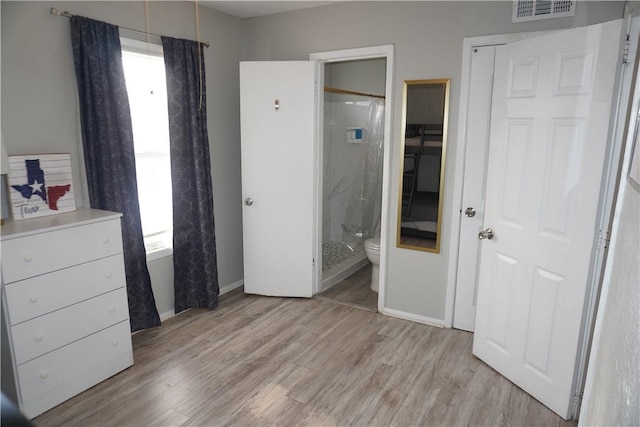 bedroom featuring light wood finished floors, baseboards, visible vents, and ensuite bathroom