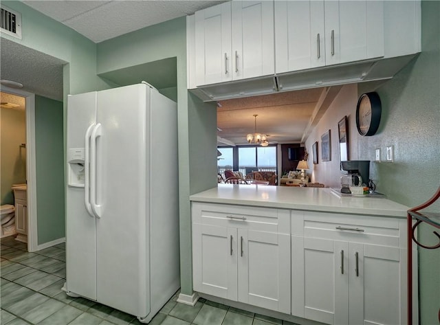 6109 State Highway 361 Unit 601, Port Aransas, TX 78373 - kitchen featuring white refrigerator with ice dispenser, white cabinets, light countertops, light tile patterned floors, and a textured ceiling