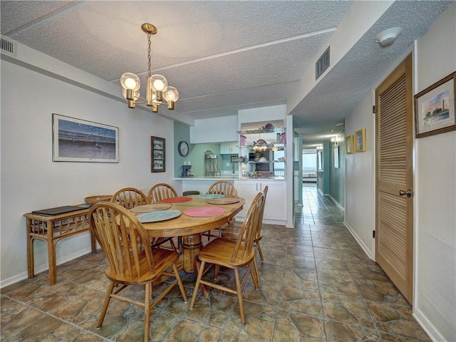 6109 State Highway 361 Unit 601, Port Aransas, TX 78373 - dining space with a chandelier, a textured ceiling, stone finish flooring, and baseboards