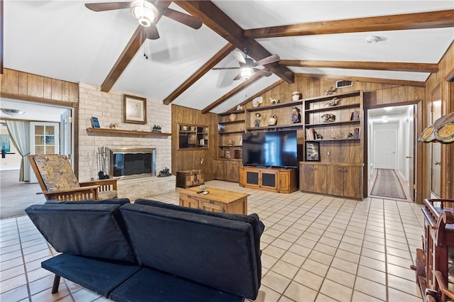 living room featuring wood walls, vaulted ceiling with beams, light tile patterned floors, a fireplace, and built in shelves