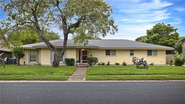 single story home with cooling unit and a front lawn