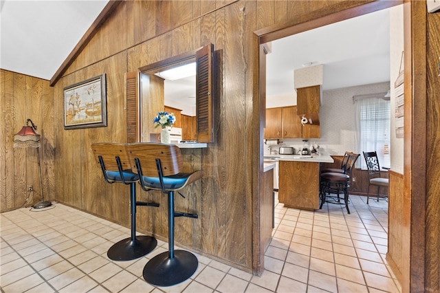 interior space with lofted ceiling, light tile patterned flooring, and wooden walls