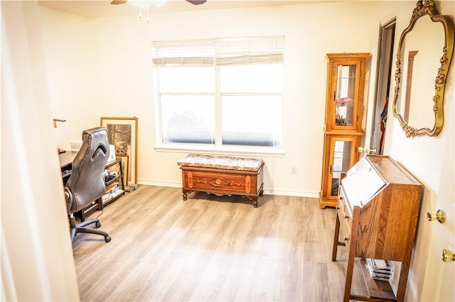 office with light wood-type flooring and ceiling fan