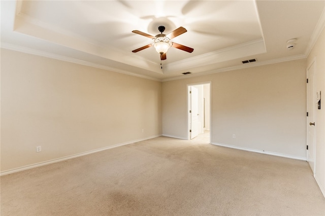 carpeted empty room featuring a tray ceiling, ceiling fan, and crown molding