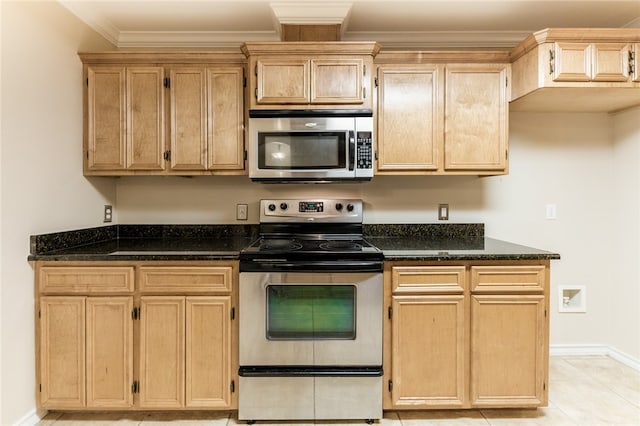 kitchen featuring light tile patterned floors, stainless steel appliances, crown molding, and dark stone countertops