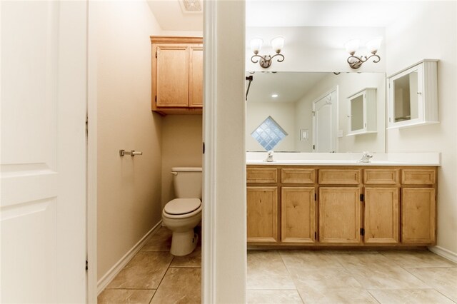 bathroom with tile patterned flooring, vanity, an inviting chandelier, and toilet