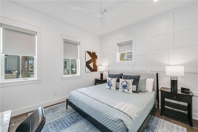 bedroom featuring multiple windows, wood finished floors, baseboards, and a ceiling fan