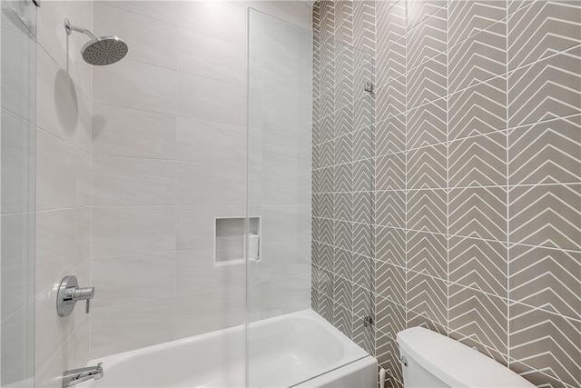 bathroom with bath / shower combo with glass door, toilet, and tile walls