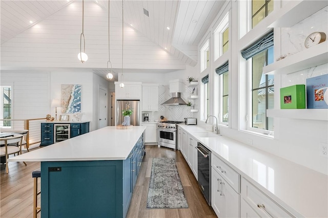 kitchen with stainless steel appliances, open shelves, blue cabinetry, white cabinets, and wood finished floors
