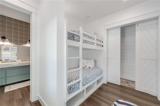 bedroom featuring wood finished floors, connected bathroom, and baseboards