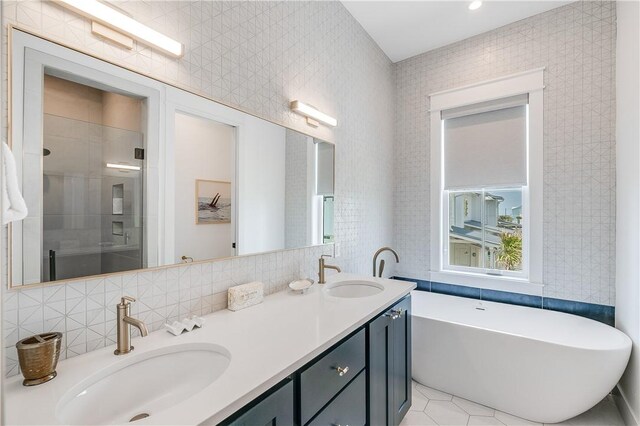 bathroom featuring tile walls, a shower stall, double vanity, a freestanding tub, and tile patterned flooring