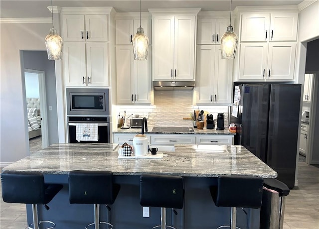 kitchen featuring hanging light fixtures, a center island, white cabinets, and black appliances