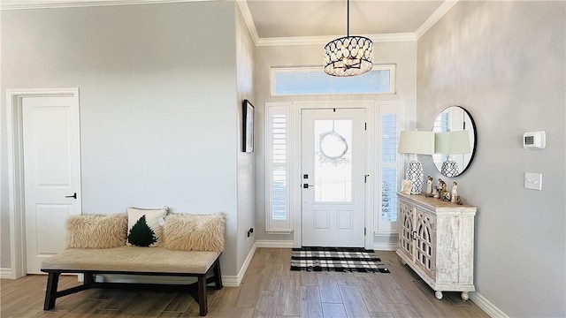 foyer with hardwood / wood-style flooring, crown molding, and a notable chandelier