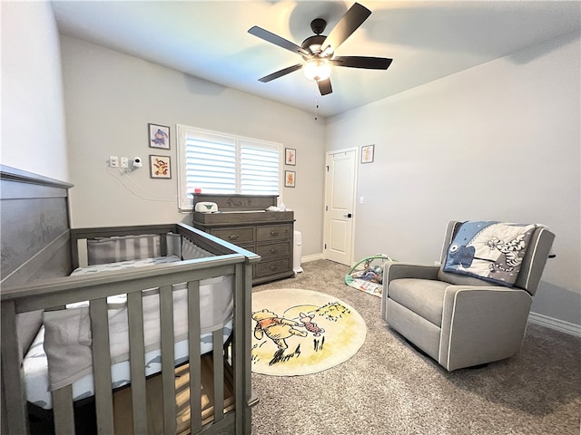 bedroom featuring a nursery area, ceiling fan, and carpet