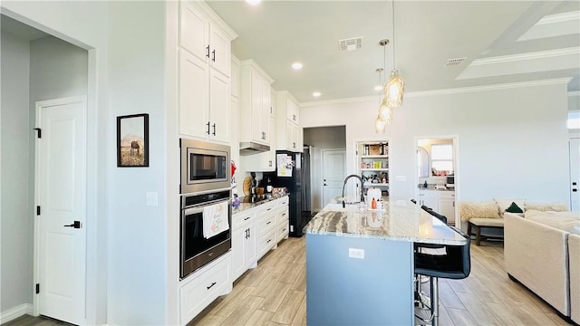 kitchen with pendant lighting, an island with sink, white cabinetry, a kitchen bar, and stainless steel appliances