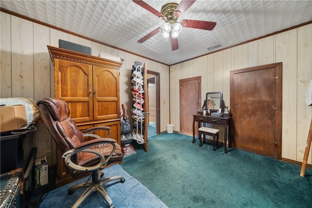 office featuring dark colored carpet, ceiling fan, ornamental molding, and wooden walls