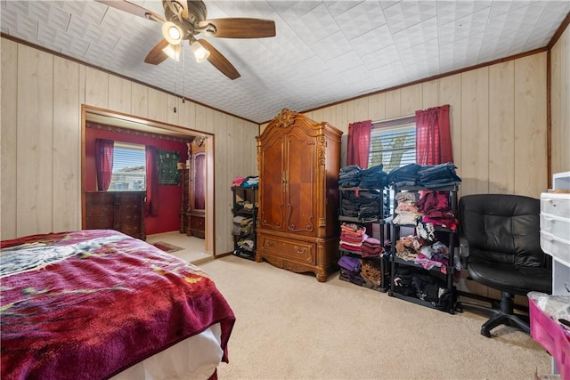 carpeted bedroom featuring ceiling fan, ornamental molding, and wood walls