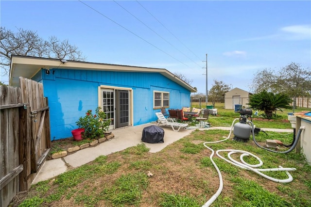 rear view of property featuring a storage unit, a patio area, and a yard