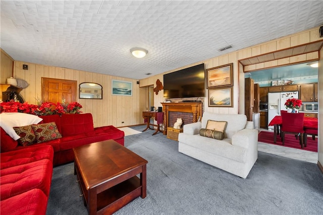 carpeted living room with a brick fireplace and wood walls