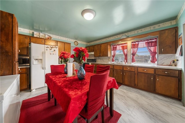 kitchen with white refrigerator with ice dispenser, backsplash, and sink